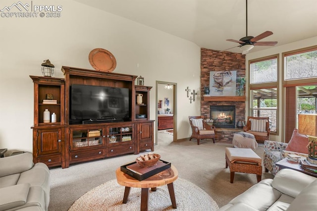 living room featuring a ceiling fan, a stone fireplace, light carpet, and high vaulted ceiling