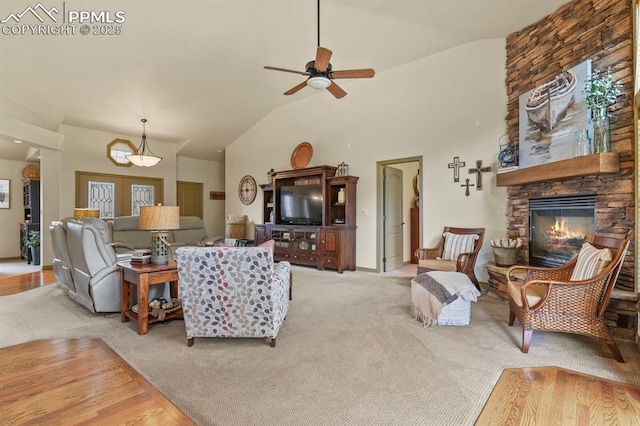 living area with a ceiling fan, carpet, lofted ceiling, and a fireplace