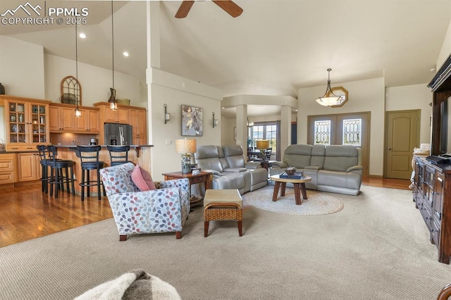 living area featuring ceiling fan, a high ceiling, carpet, recessed lighting, and wood finished floors