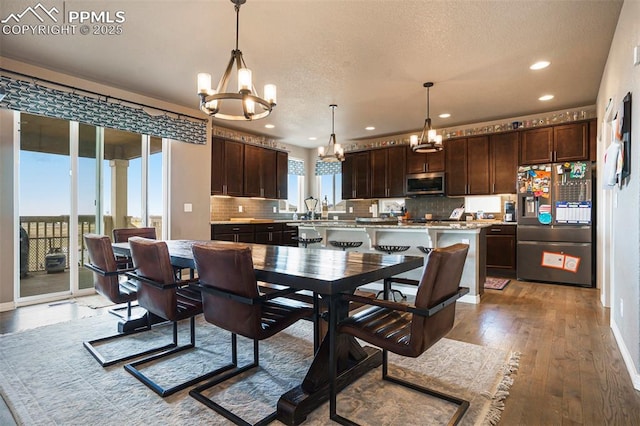12857 Morning Breeze Way, Peyton, CO 80831 - dining space featuring baseboards, recessed lighting, a textured ceiling, light wood finished floors, and a notable chandelier