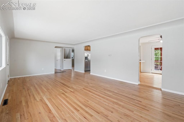 735 N Walnut St, Colorado Springs, CO 80905 - unfurnished living room with arched walkways, baseboards, light wood-type flooring, and visible vents