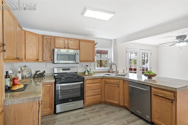 735 N Walnut St, Colorado Springs, CO 80905 - kitchen with a peninsula, light wood-type flooring, tile counters, a sink, and appliances with stainless steel finishes