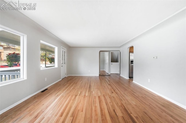 735 N Walnut St, Colorado Springs, CO 80905 - unfurnished living room with arched walkways, baseboards, visible vents, and light wood-style floors
