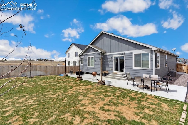 back of house featuring a lawn, a patio area, board and batten siding, and a fenced backyard