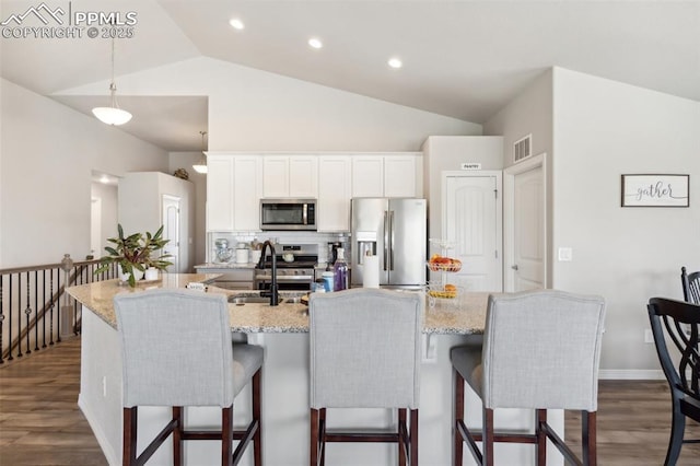 kitchen featuring lofted ceiling, decorative backsplash, a sink, appliances with stainless steel finishes, and dark wood-style flooring
