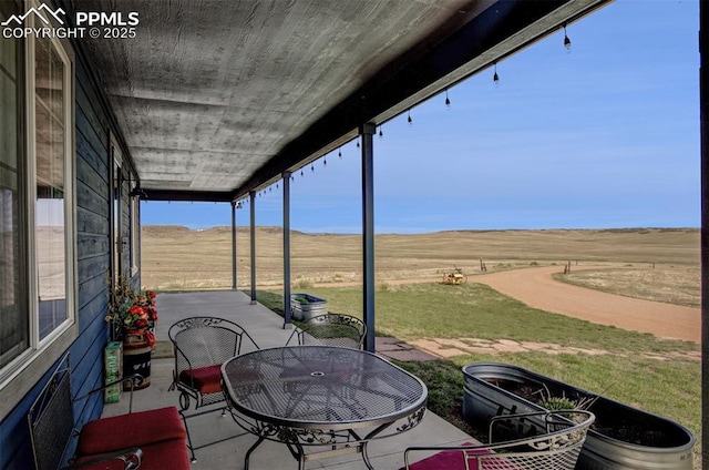 view of patio / terrace with fence, a rural view, and outdoor dining area