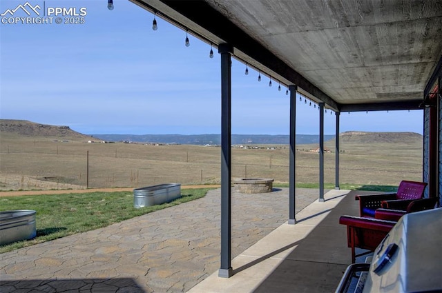 view of patio / terrace featuring fence, a fire pit, and a rural view