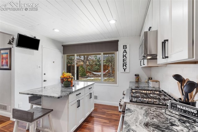 kitchen featuring a breakfast bar, white cabinetry, dark wood-style floors, and light stone counters