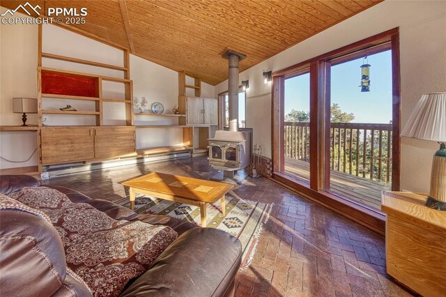 living area with a wood stove, wooden ceiling, brick floor, a baseboard radiator, and high vaulted ceiling