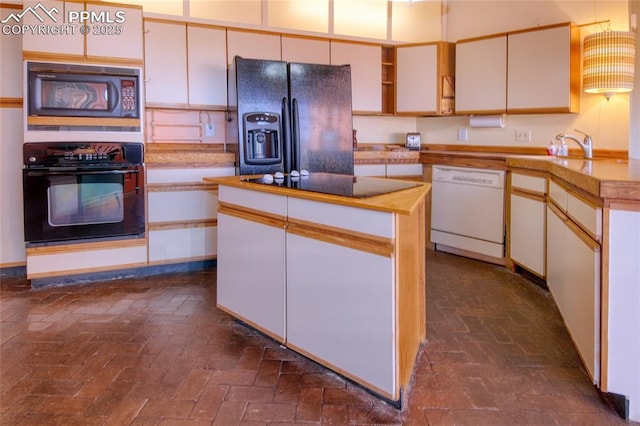 kitchen featuring white cabinets, a sink, brick floor, a center island, and black appliances