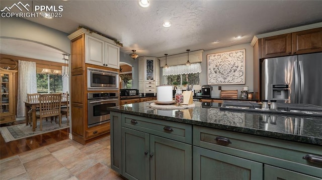 17770 Radbourne Ct, Monument, CO 80132 - kitchen featuring appliances with stainless steel finishes, arched walkways, dark stone counters, recessed lighting, and decorative light fixtures