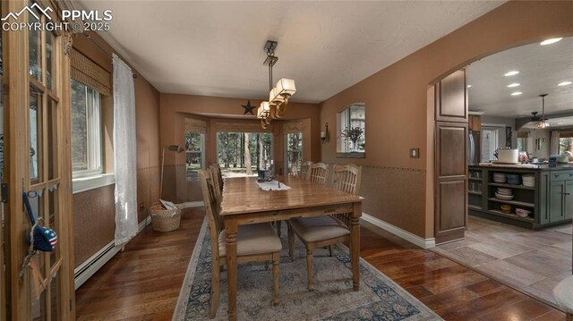 17770 Radbourne Ct, Monument, CO 80132 - dining area with a baseboard heating unit, arched walkways, wood finished floors, a chandelier, and baseboards