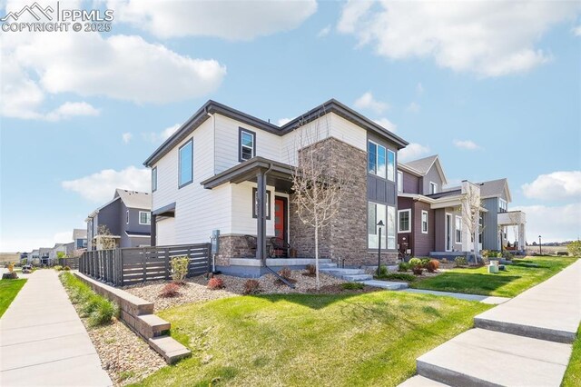 contemporary house with a residential view, fence, a front yard, and stone siding