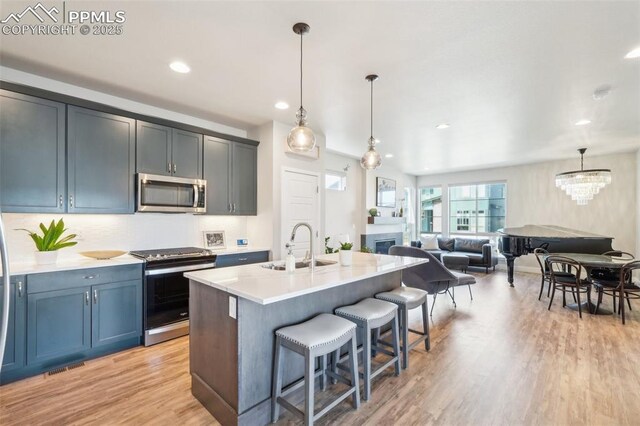 kitchen with a breakfast bar, light wood-type flooring, light countertops, a sink, and stainless steel appliances