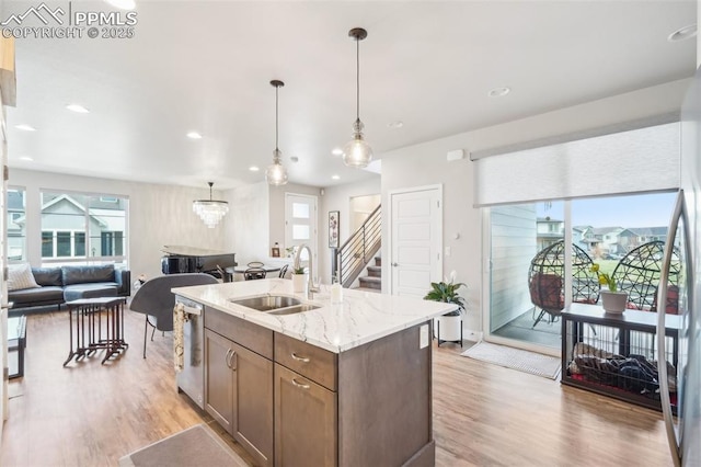 kitchen with stainless steel dishwasher, a sink, light wood-style flooring, and open floor plan