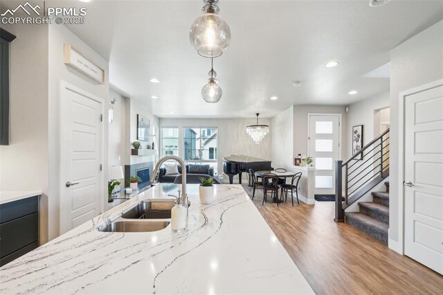 kitchen featuring hanging light fixtures, a healthy amount of sunlight, a sink, and wood finished floors