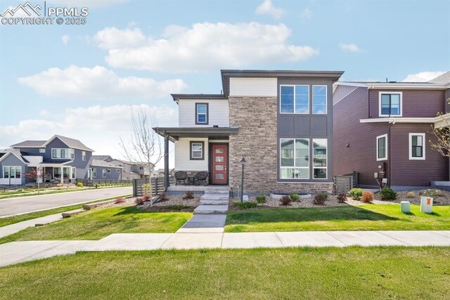 view of front facade with a porch, a front yard, a residential view, and stone siding