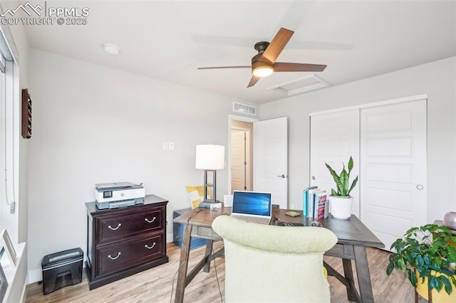 home office with attic access, a ceiling fan, light wood finished floors, and visible vents
