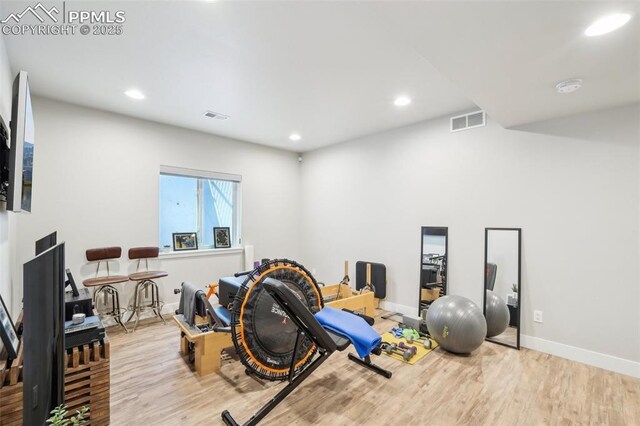 exercise area with baseboards, recessed lighting, wood finished floors, and visible vents