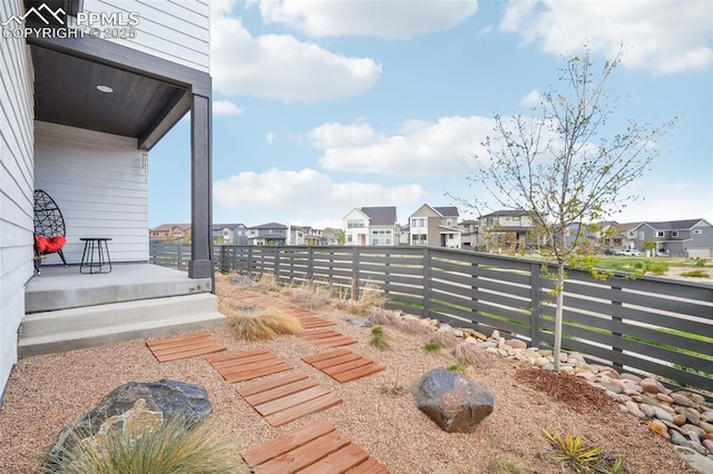 view of yard with a porch, fence, and a residential view