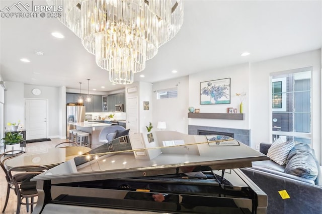 dining area featuring baseboards, recessed lighting, light wood-type flooring, a multi sided fireplace, and a notable chandelier