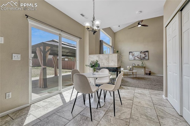 dining space featuring ceiling fan with notable chandelier, baseboards, lofted ceiling, and visible vents