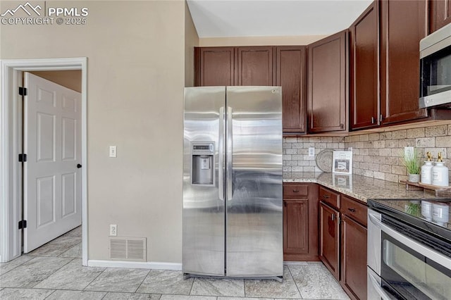 kitchen featuring visible vents, baseboards, light stone counters, backsplash, and stainless steel appliances