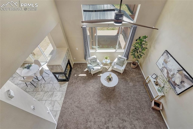 carpeted living area featuring plenty of natural light, baseboards, and a high ceiling