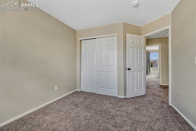 unfurnished bedroom with carpet flooring, baseboards, and a closet