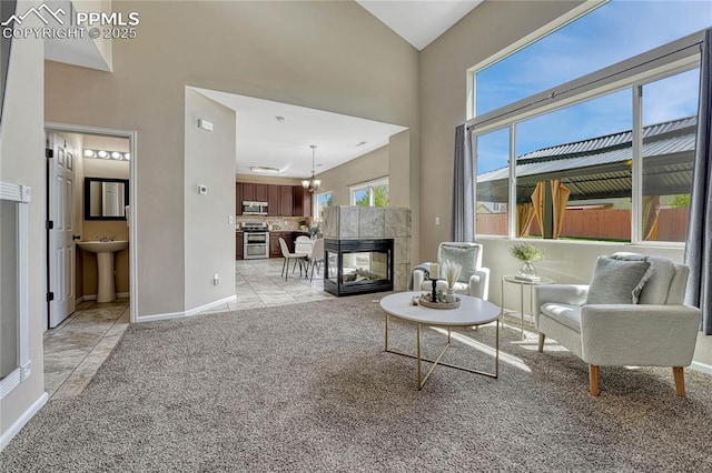 living area with light tile patterned floors, baseboards, a towering ceiling, and light colored carpet