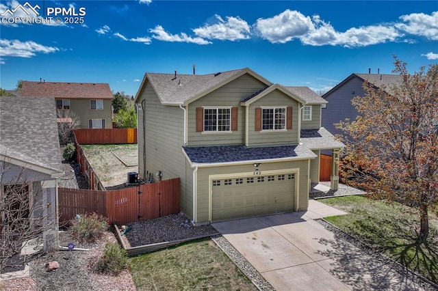 view of front of house with concrete driveway, an attached garage, fence, and a shingled roof