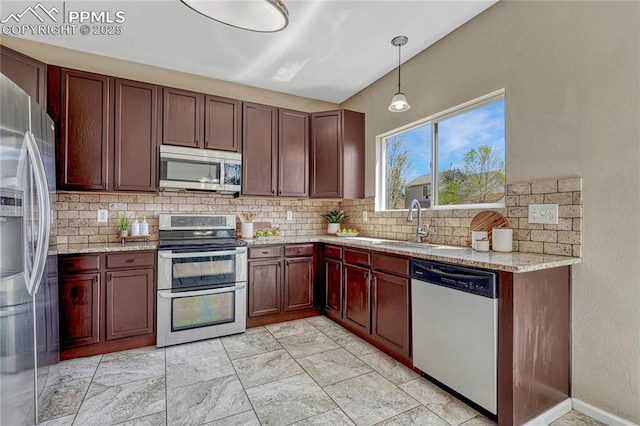 kitchen featuring decorative backsplash, pendant lighting, light stone counters, a sink, and appliances with stainless steel finishes
