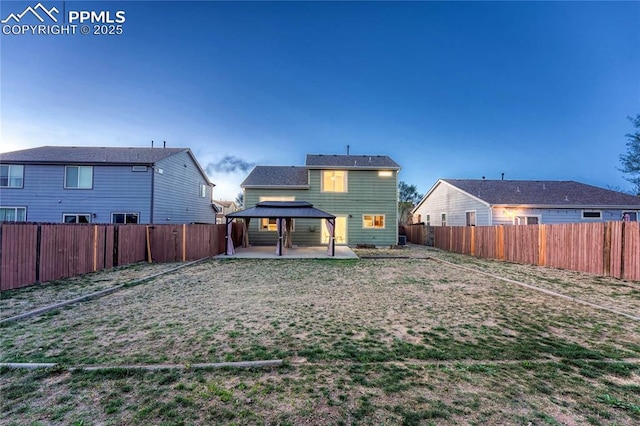 rear view of property featuring a gazebo, a fenced backyard, a patio area, and a lawn