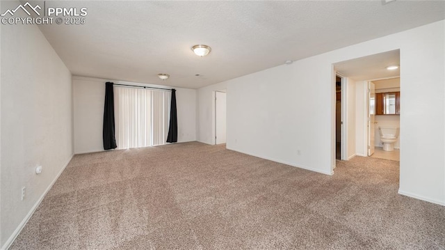 carpeted spare room featuring baseboards