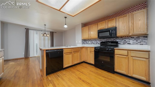 kitchen featuring black appliances, light countertops, light brown cabinets, and light wood-style floors