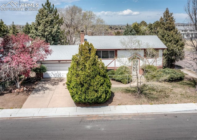 view of front of property with a chimney, a garage, and concrete driveway