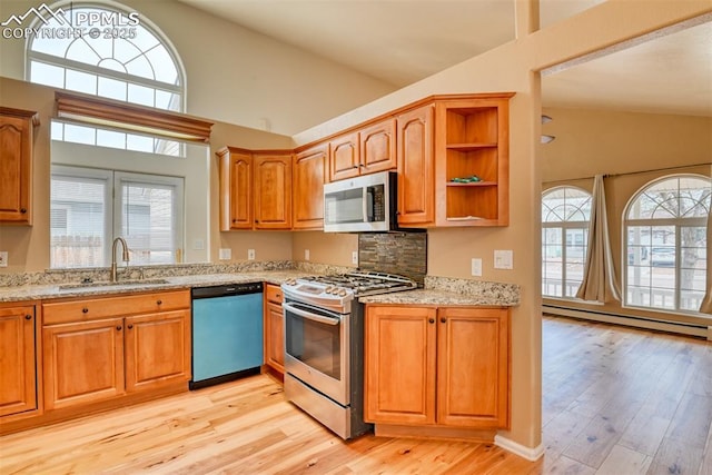 kitchen with light stone countertops, stainless steel appliances, a sink, and a wealth of natural light