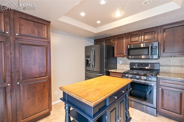 kitchen with appliances with stainless steel finishes, a raised ceiling, light tile patterned floors, decorative backsplash, and recessed lighting