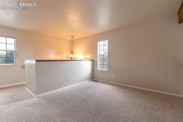 carpeted spare room with a chandelier and baseboards