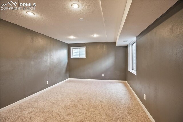 basement featuring carpet floors, a textured ceiling, and baseboards