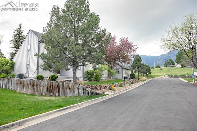 view of asphalt road with a mountain view and curbs