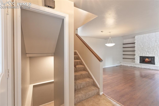 staircase with baseboards, a fireplace, and wood finished floors
