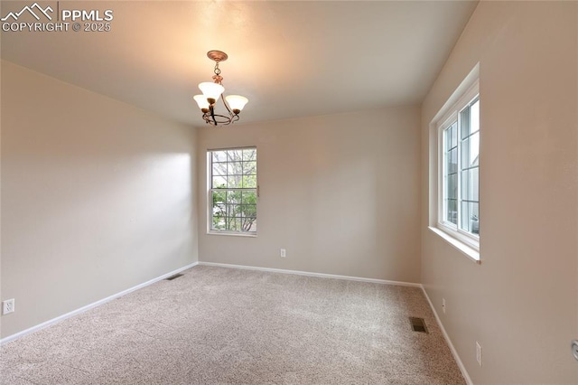 carpeted spare room featuring a chandelier and baseboards