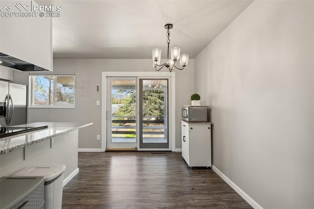 doorway to outside featuring an inviting chandelier, baseboards, and dark wood-style floors
