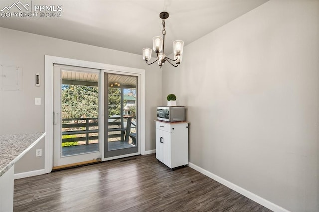 unfurnished dining area featuring baseboards, a chandelier, and dark wood-style floors