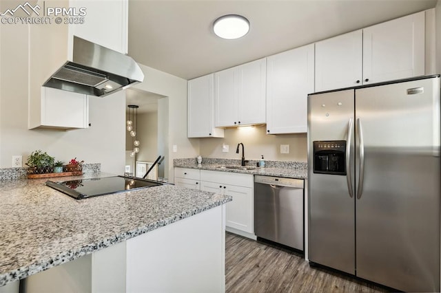 kitchen featuring a sink, wood finished floors, white cabinetry, range hood, and appliances with stainless steel finishes