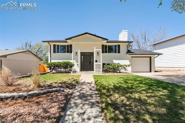 split foyer home featuring an attached garage, fence, a chimney, a front lawn, and driveway