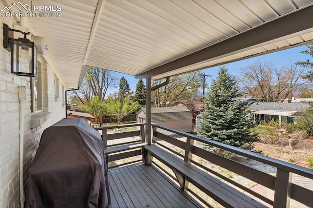 deck featuring area for grilling, a storage shed, and an outbuilding