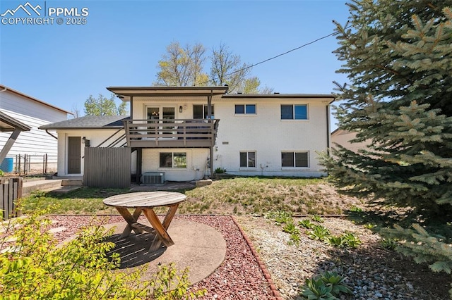 rear view of property featuring a balcony, central air condition unit, brick siding, and fence