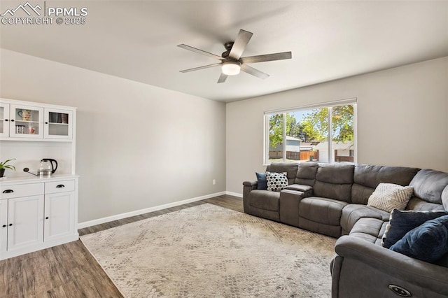 living area featuring baseboards, a ceiling fan, and wood finished floors